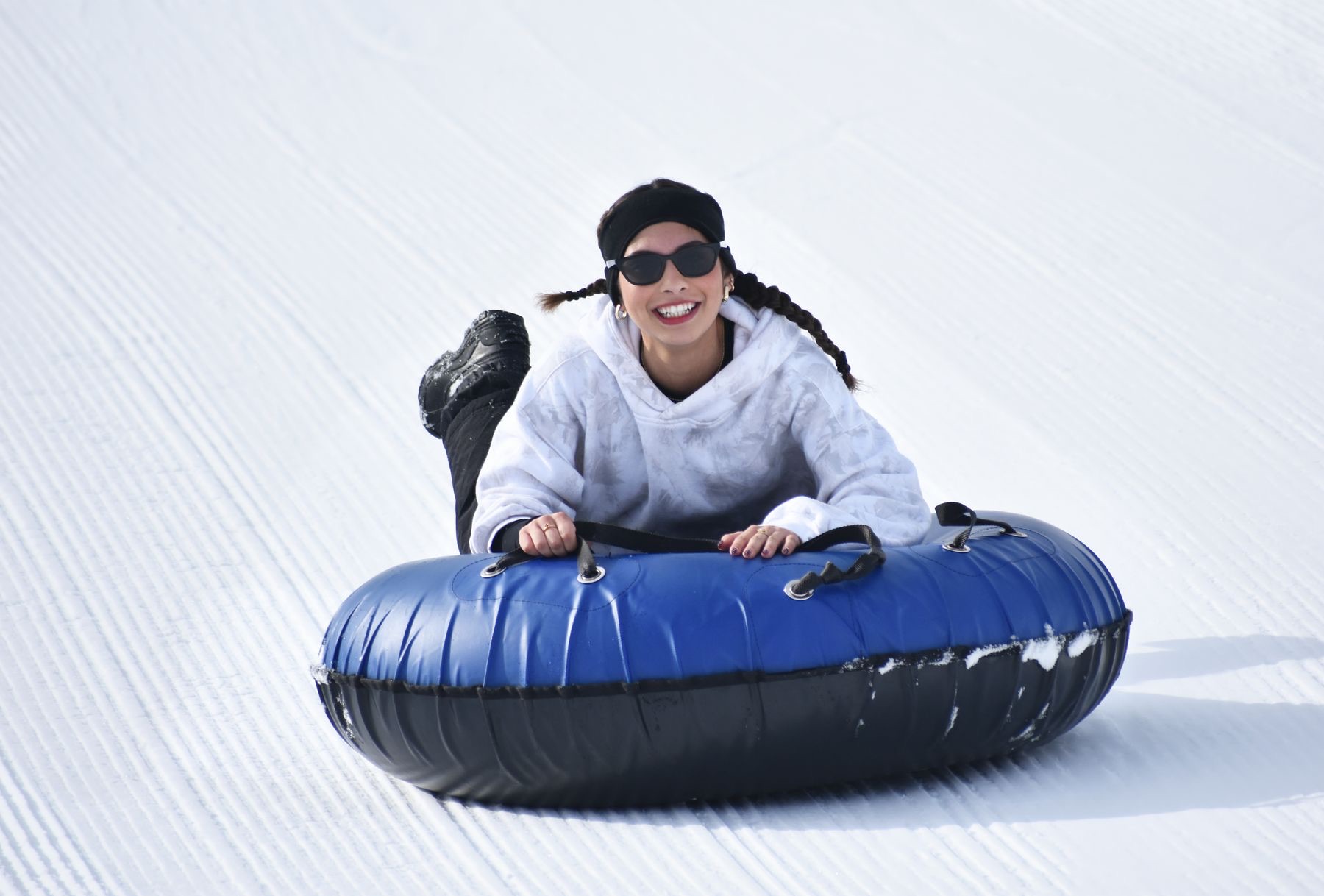 A family sliding down a slope on snow tubes